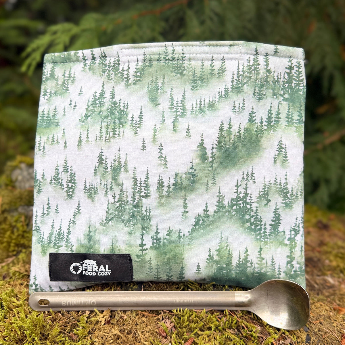 an insulated food cozy with a pattern of evergreen trees in the fog