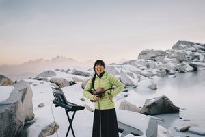Anastasia Allison of The Musical Mountaineers stands in front of a frozen lake. Photo by Karen Wang.  