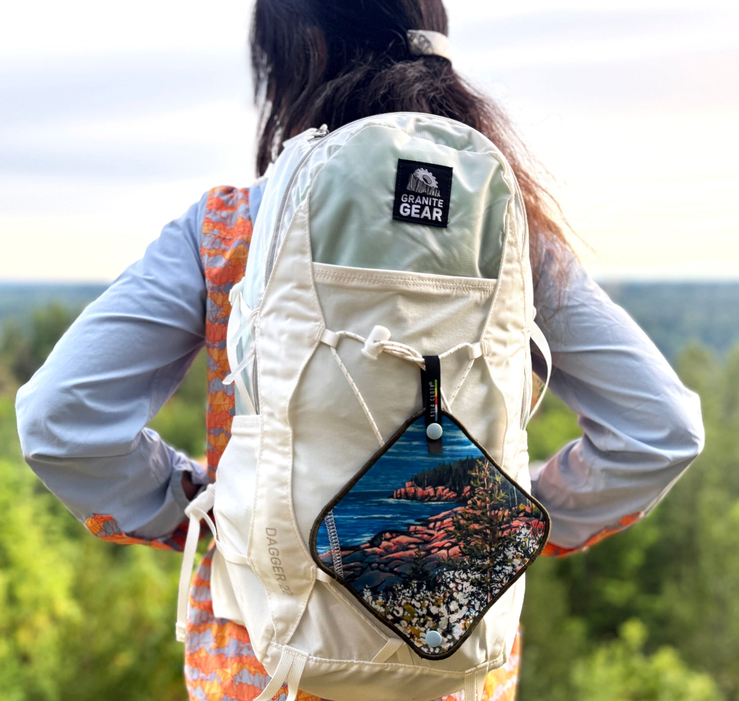 woman outside wearing a backpack with a pee cloth clipped to the backpack